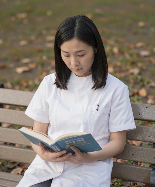 Female nurse reading a book in a park during her time off